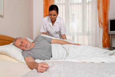 caregiver assisting elder man on bed